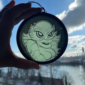 She Creature From The Black Lagoon glass round held to the sky